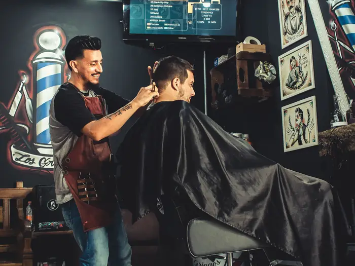 A barber cutting a customer’s hair in his shop